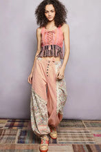 The model wears a soft pink fringe hem tank with lace detail paired with patchwork harem pants in cream and floral patterns