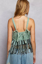 A sage green boho-style fringe hem tank with thin tied straps and black and white geometric patterns