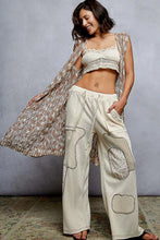 Crochet sleeveless longline cardigan with metal button and beige waffle-knit pants