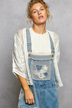 POL open front crochet cardigan with floral embroidery on blue denim overalls