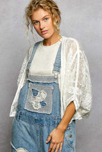 POL crochet cardigan with floral embroidery on blue denim overalls