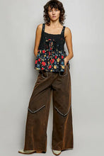 Brown wide-leg trousers with pearl trim along side seams paired with floral woven patch ribbed sleeveless top