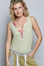 A light green ribbed knit sleeveless tank top with a contrast floral neckband and button closure