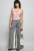 Wide-leg denim pants with patchwork light fabric panels and subtle embroidery paired with a pol ribbed v-neck tank with contrast floral neckband
