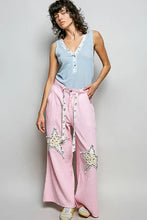 Pink wide-leg pants with star-shaped patchwork and drawstring waistband paired with a pol ribbed v-neck tank with contrast floral neckband