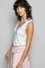 A soft white knitted sleeveless tank with v-neckline and blue contrast floral neckband embroidery edges