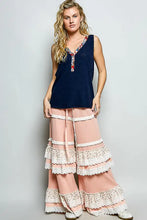 A woman wears a navy blue ribbed sleeveless tank with a contrast floral neckband embroidered along the neckline