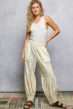 Cream-colored patchwork harem pants with floral pattern and ruffled cuffs paired with a pol round neck cami tank with lace trim