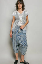 A woman wearing a layered POL subtle stripe pattern cross-back string top with center tie detail in white and light blue lace