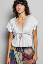 White textured short sleeve blouse with lace trim and tied waistband for a polished casual look
