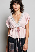Soft pink short sleeve blouse with ruffles v-neckline lace trim and gathered waist tied with matching fabric ties