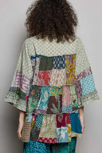 A vibrant pol tiered floral patchwork women’s jacket with layered colorful floral fabric pieces in green red blue yellow and beige