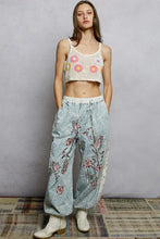 Light blue denim pants with intricate pink and red floral embroidery worn with a pol u-neck cropped crochet cami