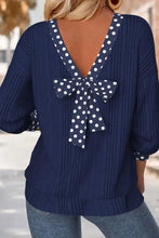 Navy blue ribbed knit long sleeve blouse showing back side with white polka dot bowknot at neckline