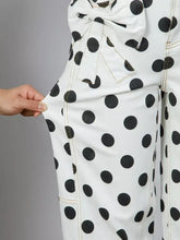 White high-waisted jeans with black polka dots and a large bow detail at the waist for a stylish look