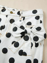 White denim polka dot high-waisted jeans with black dots and a matching fabric bow at the waist
