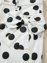 White denim high-waisted jeans with black polka dots and a matching fabric bow at the waist