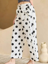 White wide-leg high-waisted jeans with black polka dots and a tied bow waist for stylish casual wear