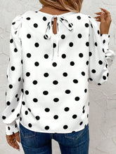 White blouse with black polka dots and long sleeves featuring a tie-back detail at the neckline for a polished look