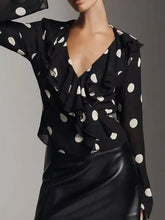 Black polka dot ruffle v neck blouse with white circular patterns and a ruffled neckline in lightweight fabric