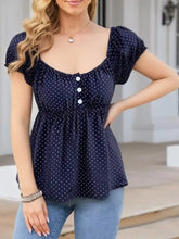 Navy blue short sleeve blouse with white polka dots and a gathered waistline for casual wear