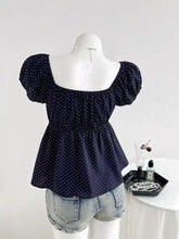 Navy blue polka dot short sleeve blouse with puffed sleeves and peplum hem made from lightweight fabric