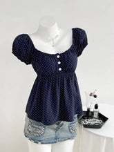 Navy blue polka dot short sleeve blouse with white buttons and gathered waistline ideal for casual wear