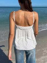 White polka dot v neck flowy cami with spaghetti straps made of lightweight fabric for a stylish summer look