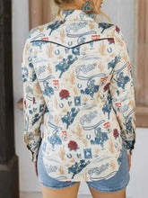 Printed button up long sleeve shirt in cream with vibrant blue cowboys, horseshoes, cacti, red roses, and rodeo script