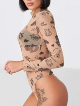 A sheer beige printed mock neck long sleeve bodysuit with black illustrated symbols and phrases
