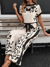 Cremefarbener Jumpsuit mit weitem Bein, schwarzen Blumenmustern und Gürtel