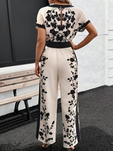Cremefarbener Jumpsuit mit weitem Bein, schwarzer Blumenstickerei und schwarzem Gürtel