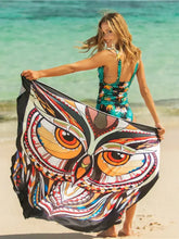 Woman in printed spaghetti strap cover up holding colorful owl-print beach towel