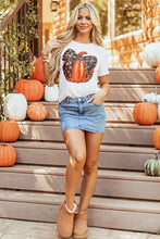 Women’s pumpkin graphic tee with black orange accents, denim skirt, tan suede boots