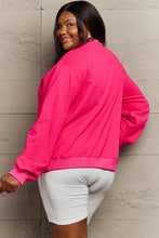 Woman in pumpkin spice graphic sweatshirt, hot pink long-sleeved top, white biker shorts