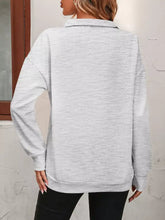 A heather gray quarter zip dropped shoulder sweatshirt with ribbed cuffs made from slightly stretchy material suitable for machine wash cold