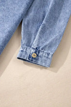 Light blue long sleeve denim dress with raw hem and a single beige button on the cuff of the sleeve