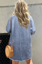 Woven circular rattan crossbody bag with tan leather strap complementing raw hem long sleeve denim dress