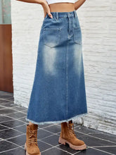 A mid-blue raw hem denim skirt with faded wash, two front pockets, and waist stretch for comfortable wear