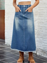 A mid-blue denim skirt with raw hem, two front pockets, and waist stretch in a buttoned design