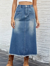 A mid-blue denim skirt with a high waist stretch elastic waistband, raw hem, button details, and front pockets