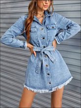 A light-wash denim dress with raw hem collared neck long sleeves button front and belted waist
