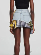 Light-wash raw hem denim mini skirt with layered ruffled hem and yellow and gray plaid patch details