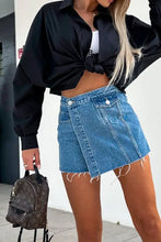 Woman in raw hem denim skorts with black shirt and brown backpack