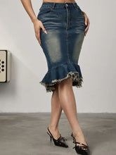 A mid-thigh length raw hem mermaid denim skirt with flared frayed hem and subtle fading