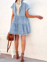 Light blue denim dress with tiered skirt and raw hem short sleeves in a raw hem short denim dress style