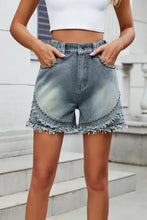 Raw hem studded denim shorts with light wash, elastic high waist, and frayed hem