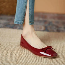 Glossy red round toe flats with patent leather bow detail