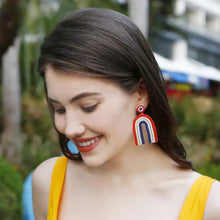 Woman in yellow top wearing colorful bead geometric dangle earrings
