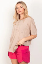 Woman in relaxed fit beige Henley shirt with patch pocket and twisted sleeve band